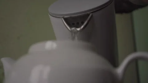 Man pours boiling water into ceramic teapot from kettle Stock Footage 243645825