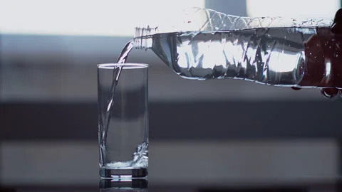 A man pours clear water from a plastic bottle into a glass Stock Footage 131367271