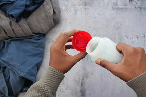Man pours detergent from a bottle while doing laundry at home Stock Photos