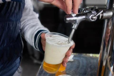 Man pours draft beer in plastic glass during picnic. Close up image with no f Stock-Fotos