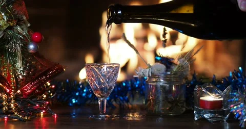 A man pours a drink from a bottle into shot glass opposite the fireplace. Video stock 161882012