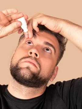 Man pours drops in red eye, has conjuctivitis or glaucoma, bad eyesight and p 스톡 사진