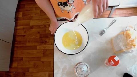 A man pours milk into a cup in which he makes dough Stock Footage 320556256