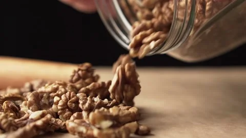 A man pours nuts from a jar onto the table, slow motion. Nutrient-rich foods. Stock Footage 143968815