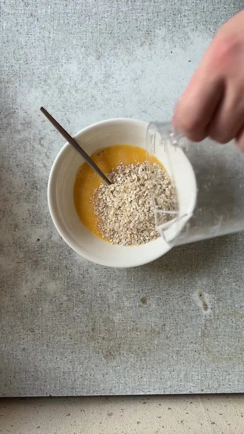 Man pours oatmeal from transparent plastic measuring cup into white bowl Stock Footage 277630397