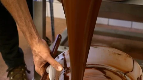 A man pours raw chocolate into large bucket after it has blended. Stock Footage 100645035