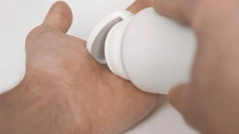 Man pours red capsules from a plastic jar into his hand palm close-up Stock Footage 202119823