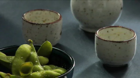 Man pours sake next to edamame Stock Footage