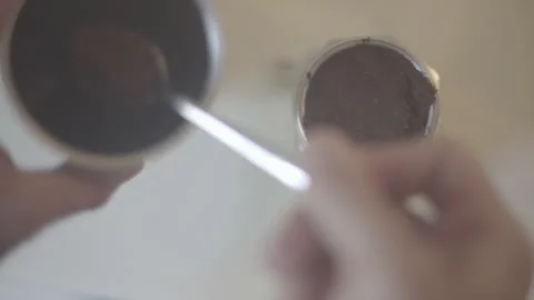 A man pours a spoon of coffee from a coffee grinder into a coffee maker. Stock Footage 265074110