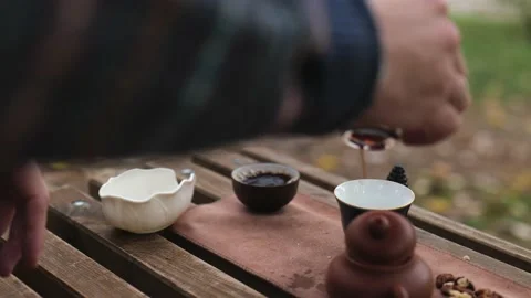A man pours strong tight pu-erh tea from a glass cup into two bowls Stock Footage 229861041