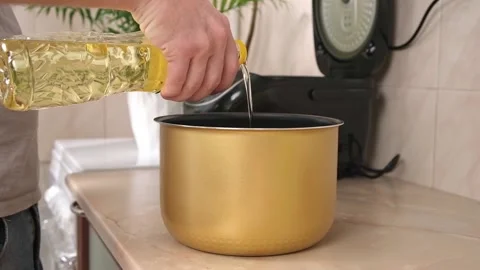 A man pours sunflower olive vegetable oil for frying into the bowl of a slow Stock Footage 224515653