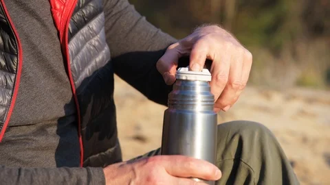 Man pours tea and takes a sip in forest. Stock Footage 120189431