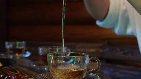 A man pours tea in a long stream into a transparent mug Stock Footage 160409334