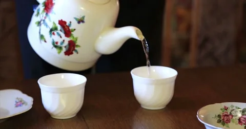 A man pours tea from a teapot into two cups. Video stock 52265644