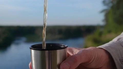 Man pours tea from thermos during hike halt. closeup hands. snack during hike. Stock Footage 231990905