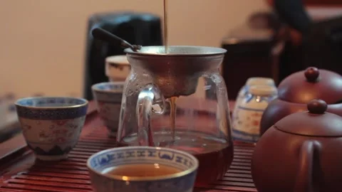 Man pours tea through a filter into transparent vessel. filtering tea is Stock Footage 278042849