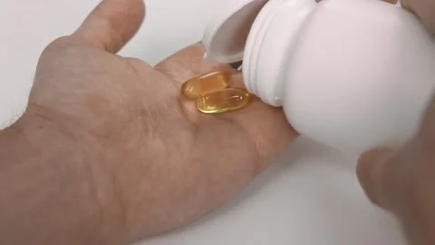 Man pours transparent capsules from a plastic jar into his hand palm Stock Footage 202119829