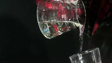 Man pours transparent liquid into empty glass from jug Stock Footage 306594230