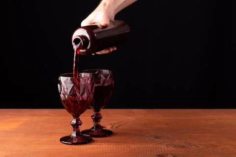 A man pours wine into glasses on a table Stock Photos