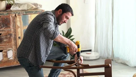Man with power drill fixing old wooden chair Stock Footage 167023976