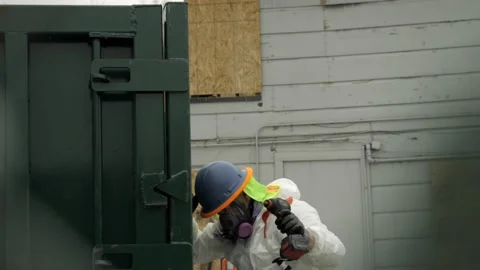 Man in PPE getting out of a construction dumpster Stock Footage 234084199
