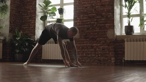 Man practice advanced yoga pose in studio with brick wall and large windows Stock Footage 113998772