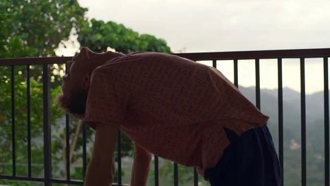 Man practice camel yoga pose at balcony at sunrise rapid slow motion Stock Footage 86651993