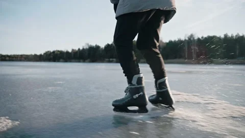 Man practice ice skating on a clear frozen lake on sunny day, making ice sparkle Video stock 170160747