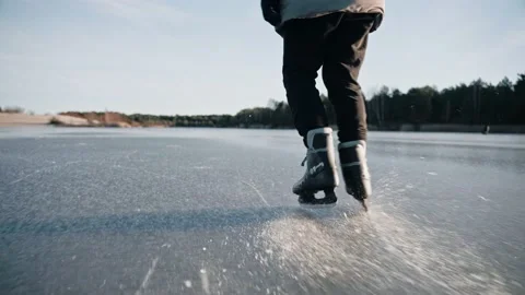 Man practice ice skating on a clear frozen lake on sunny day, making ice sparkle Stock Footage 170161481