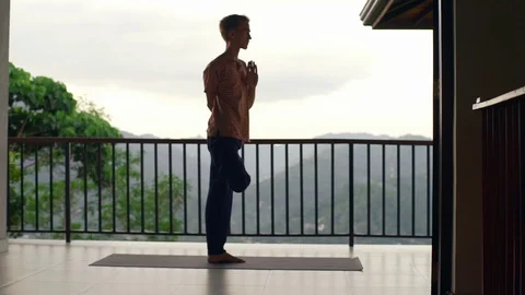 Man practice tree yoga pose at balcony at sunset rapid slow motion Stock Footage 86649234
