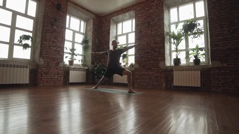 Man practice warrior yoga pose in studio with brick wall. Sporty man doing yoga Stock Footage 107103695