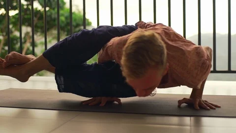 Man practice yoga eight angle pose at balcony at sunset rapid slow motion Stock Footage 86653509