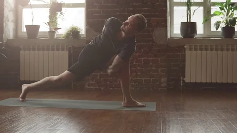 Man practice yoga pose in studio with sunbeams. Attractive man making yoga pose Video stock 107103630