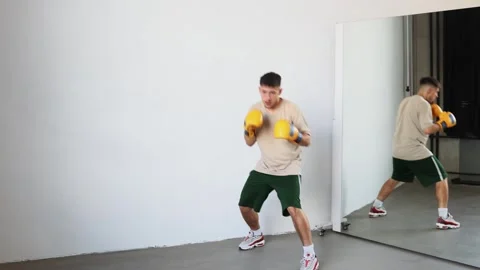 Man practices boxing technique in training room with mirror reflection Stock Footage 312383753