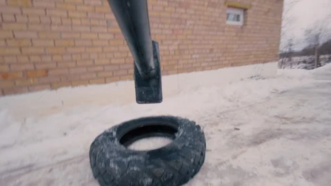 A man practices hitting a tire with a sledgehammer.From the first person. Stock Footage 321858821