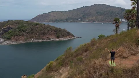 Man practices yoga on a cliff edge with stunning ocean and island views Stock Footage 310797867