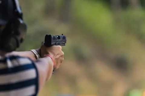 Man practicing aiming with a gun at the shooting range, medium closeup blurred Stock Photos