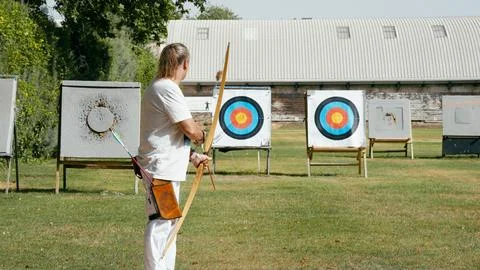Man practicing archery aiming at outdoor targets Stock Photos