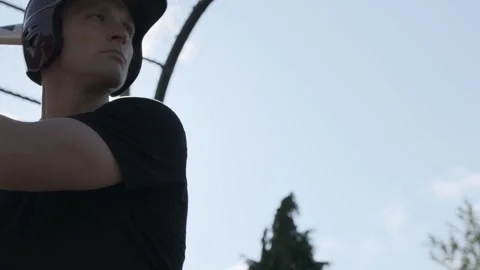 Man practicing baseball with batting helmet at local field during afternoon Stock Footage 312678090