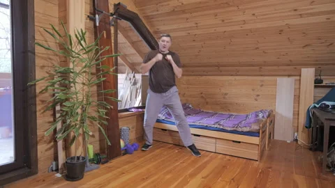 Man Practicing Boxing Movements Indoors in Wooden Room Stock Footage 335294123