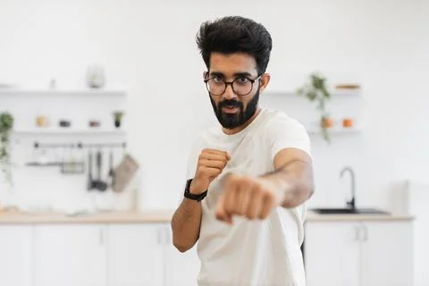 Man practicing boxing techniques in kitchen environment with determination 스톡 사진