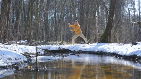 Man practicing breathing exercise in winter forest near stream Stock Footage 334840443