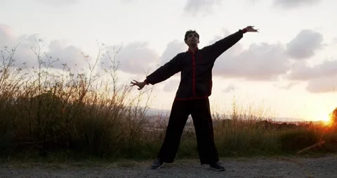 Man practicing chi kung during a sunrise on a mountain Stock Footage 136028138