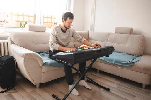 Man practicing on a digital keyboard in a bright and cozy living room, surrou 写真素材