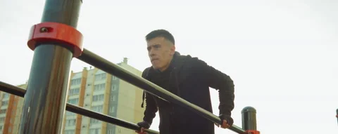 Man Practicing Dips on Parallel Bars while Training Outdoor Stock Footage 166434461