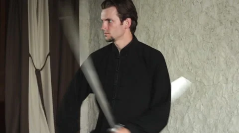 Man practicing elements of tai chi. The man rotating steel swords around a body Vidéo 64463500