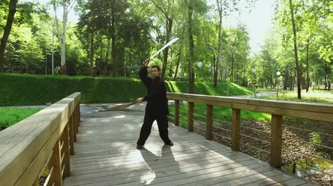 Man practicing elements of tai chi. A man rotating steel swords around a body 4K 動画素材 65255576