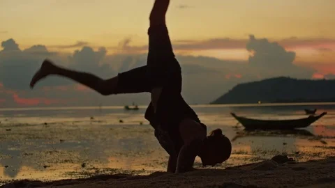 Man practicing handstand in the sea at sunset Stock Footage 74774037