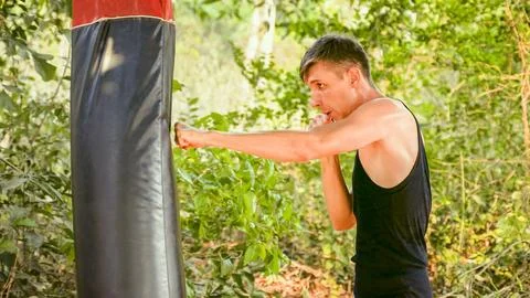Man is practicing his strikes on a punching bag in an Asian country Stock Photos