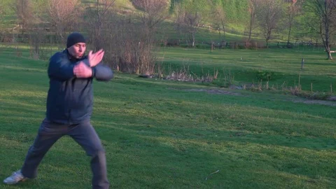Man Practicing Karate on Green Grass With Dew Makes the Kick on a Background of Stock Footage 74693003